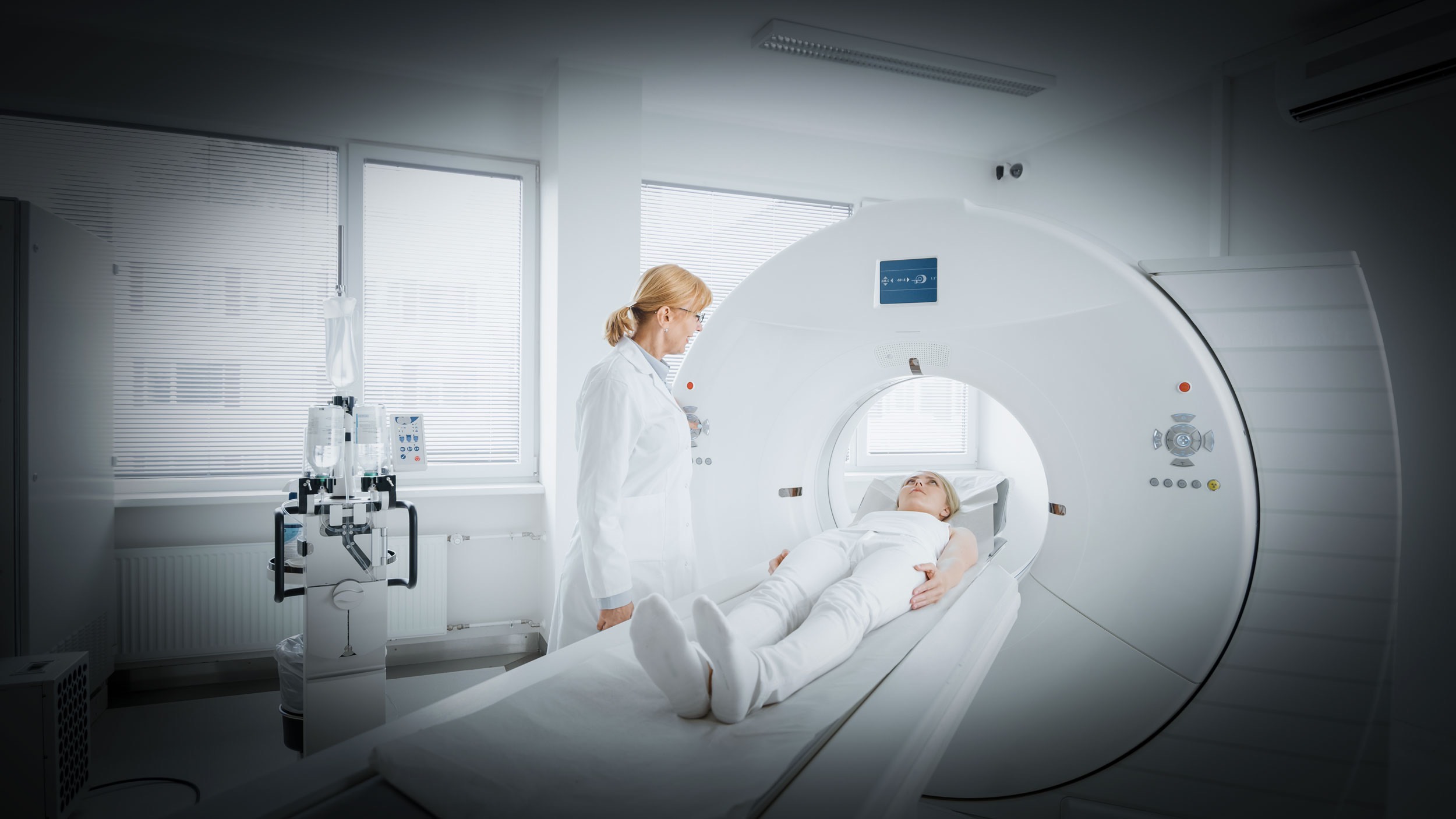In Medical Laboratory Female Radiologist Controls MRI or CT Scan with Female Patient Undergoing Procedure. High-Tech Modern Medical Equipment.